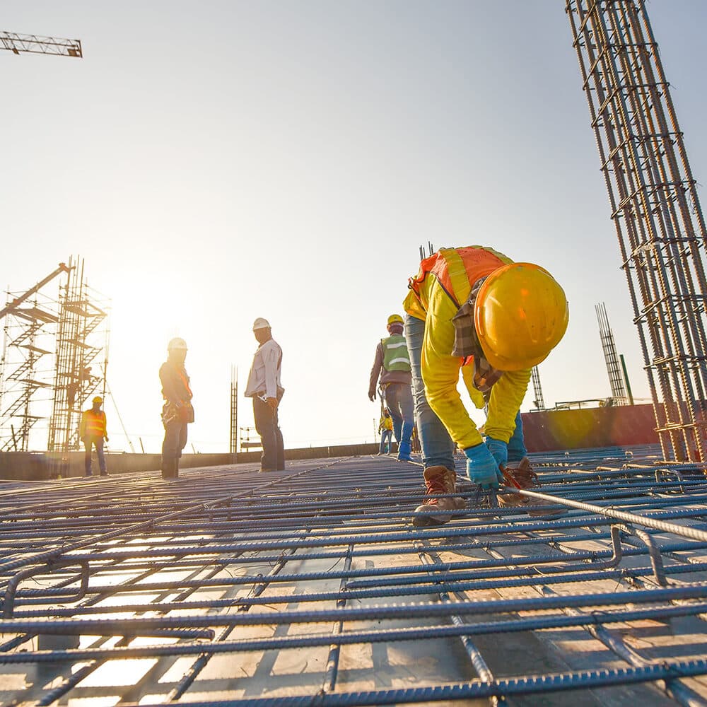 Construction crew tying rebar reinforcement on an active jobsite at sunset