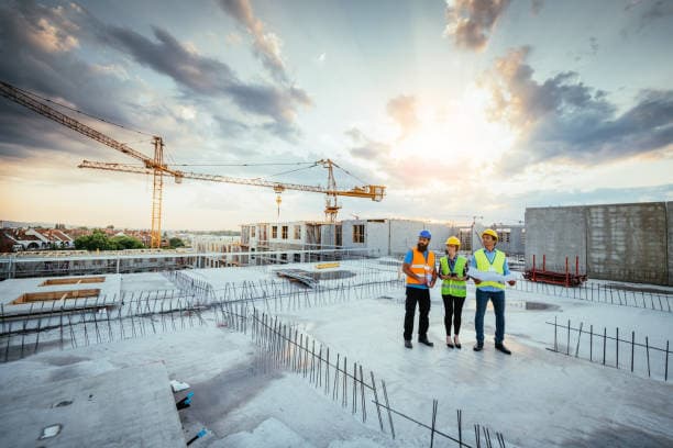 Construction team reviewing a multi-story building project at sunset